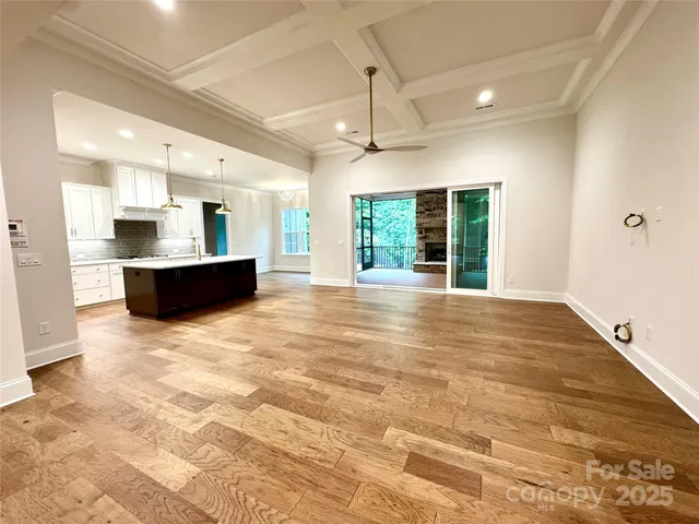 a view of an empty room with kitchen and a window