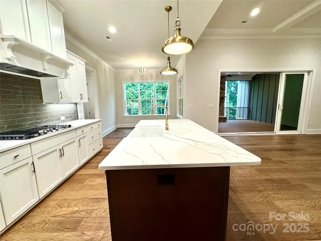 a kitchen with kitchen island granite countertop a stove a sink a refrigerator dining table and chairs