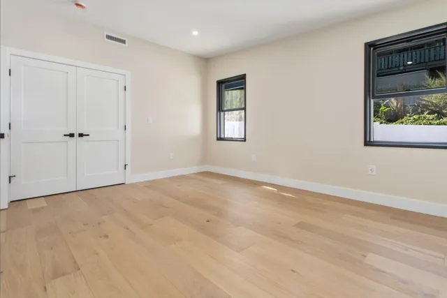 a view of an empty room with window and wooden floor