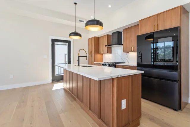 a kitchen with stainless steel appliances granite countertop a sink a stove and a wooden floors