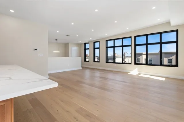 a view of an empty room with window and wooden floor