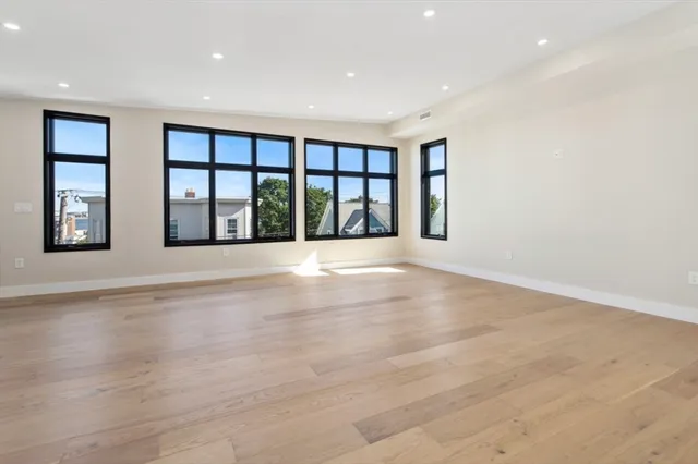 a view of an empty room with a window and wooden floor
