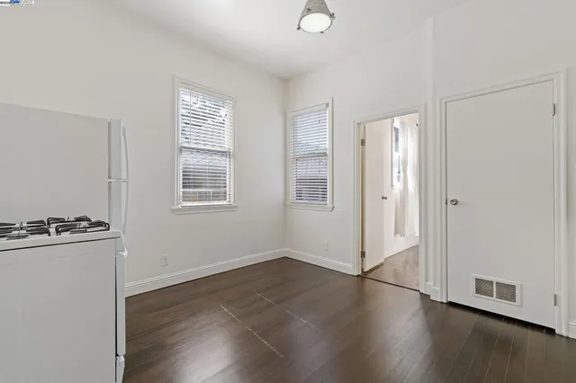 an empty room with wooden floor closet and windows