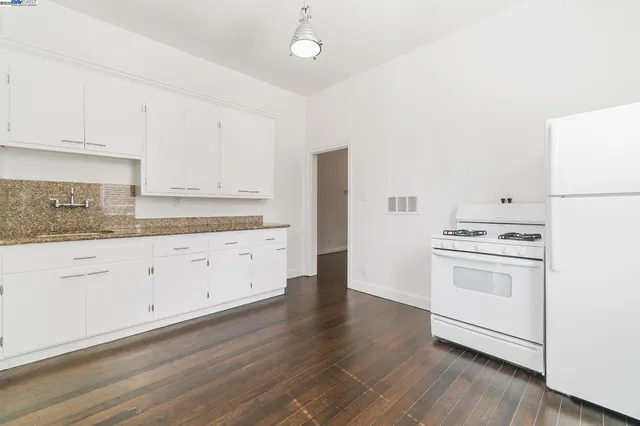 a kitchen with cabinets stainless steel appliances and wooden floor