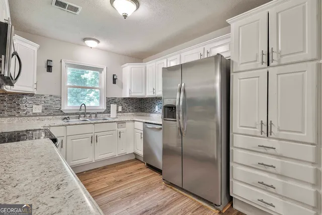 a kitchen with stainless steel appliances granite countertop a refrigerator sink and cabinets