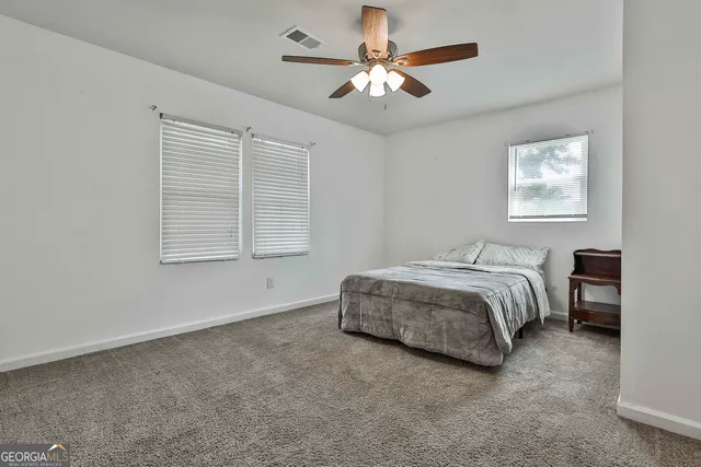 a spacious bedroom with a bed a chandelier and a window
