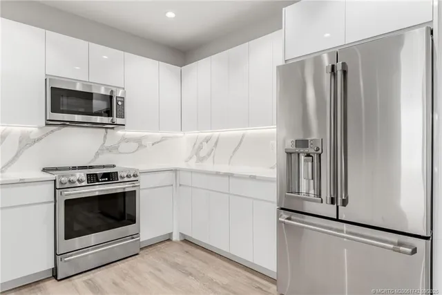 a kitchen with stainless steel appliances white cabinets white stove a microwave and a refrigerator