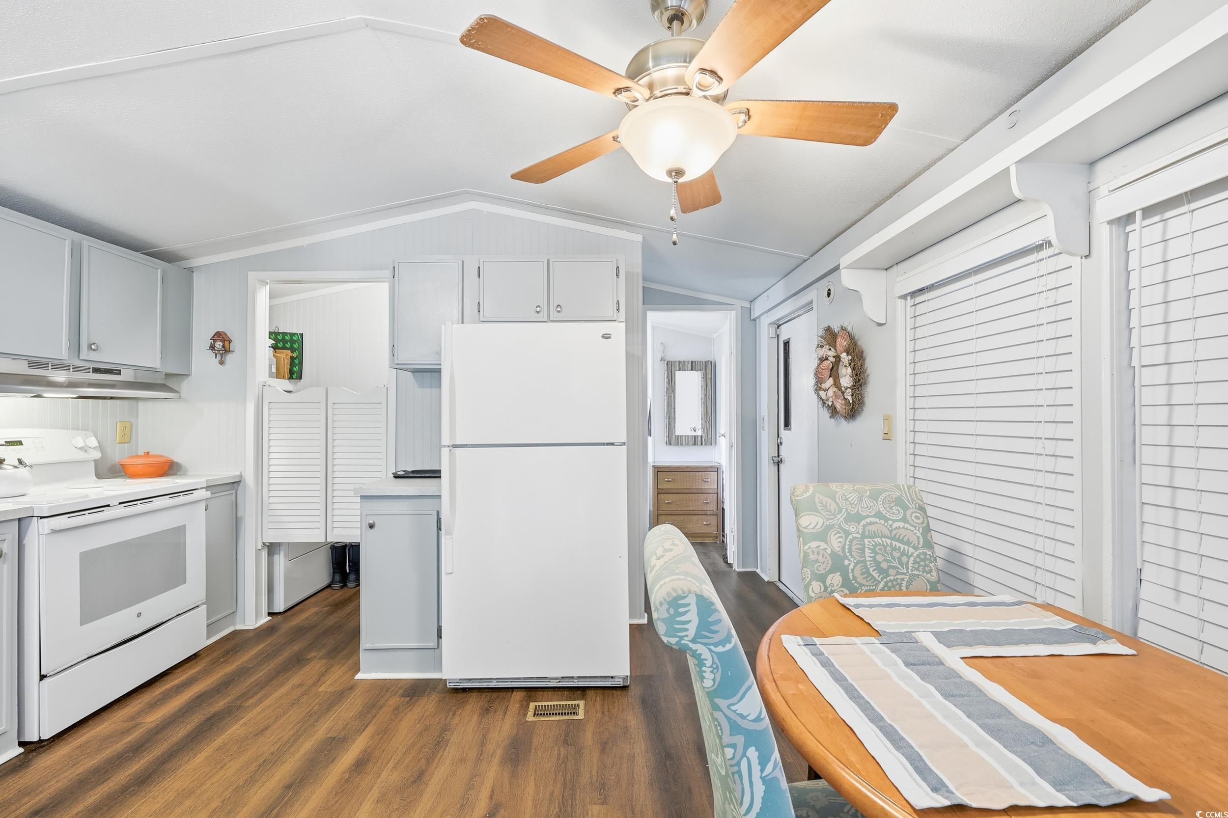 1017 Foxfire Drive North Myrtle Beach, SC 29582 - Photo 7 of 36 Kitchen with white appliances, vaulted ceiling, dark wood finished floors, light countertops, and white cabinets