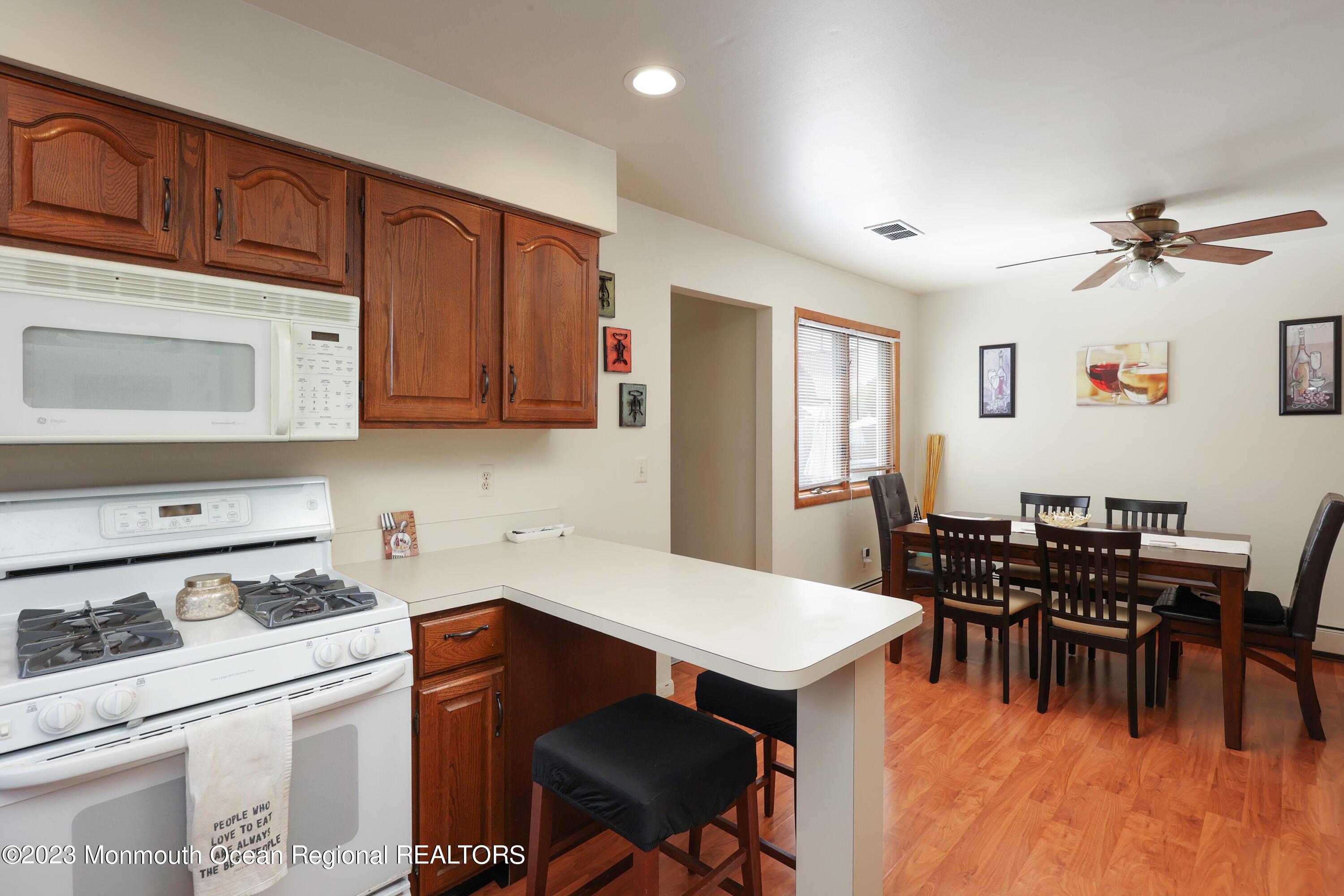 1719 River Road Belmar, NJ 07719 - Photo 17 of 32 a kitchen with stainless steel appliances wooden cabinets dining table and chairs
