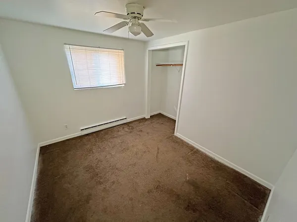 an empty room with a window and a fan