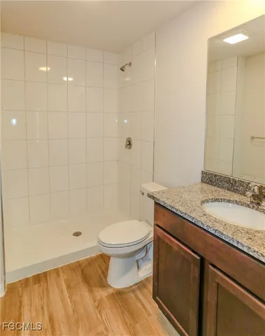 a bathroom with a granite countertop sink a toilet and shower