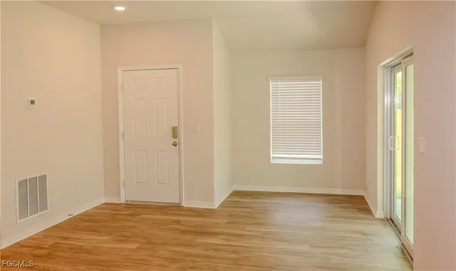 a view of an empty room with wooden floor and a window