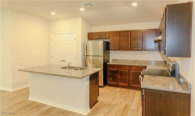 a kitchen with stainless steel appliances granite countertop a sink and a refrigerator