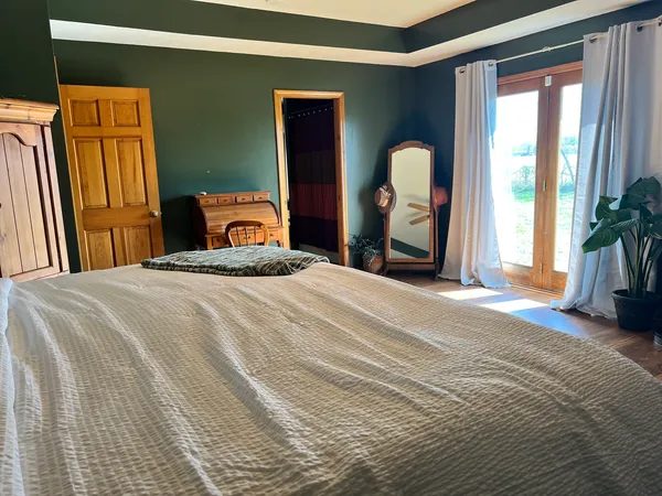 a bedroom with a bed and a large mirror next to a window