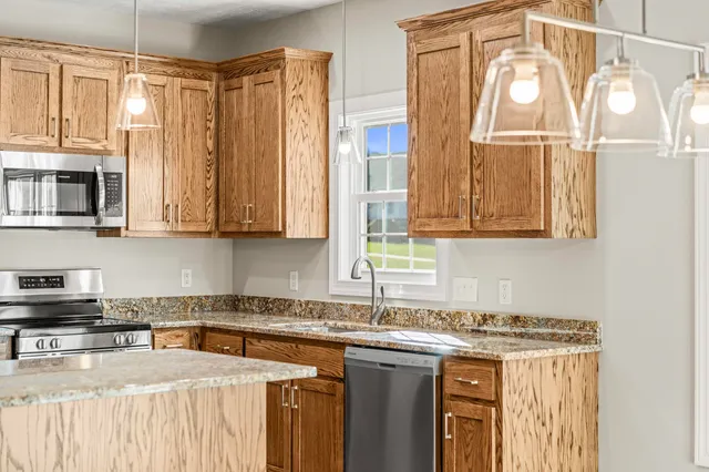 a large kitchen with stainless steel appliances granite countertop a stove and a refrigerator