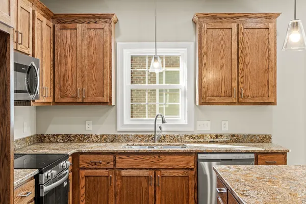 a kitchen with stainless steel appliances granite countertop a stove a sink and a microwave