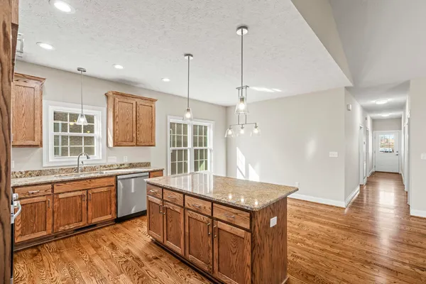 a kitchen with stainless steel appliances granite countertop a sink a stove and a wooden floors