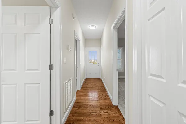 a view of a hallway with a closet and wooden floor
