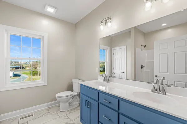 a bathroom with a double vanity sink toilet and a window