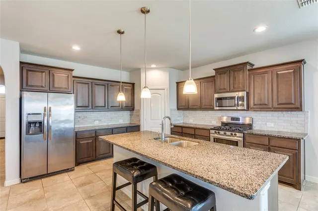 a kitchen with granite countertop a stove refrigerator and microwave