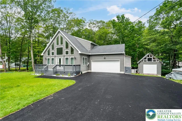 a view of a house with a big yard and large trees