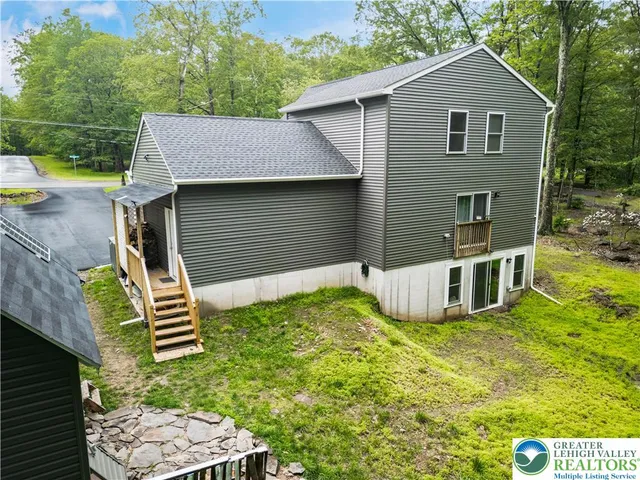 an aerial view of residential house with outdoor space and trees all around