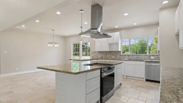 a large kitchen with granite countertop a stove a sink a window and a fireplace