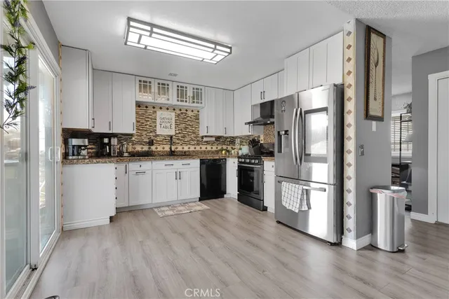 a kitchen with stainless steel appliances granite countertop a stove a sink and white cabinets