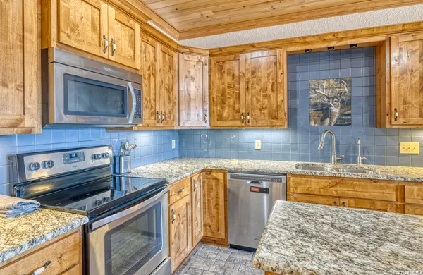 a kitchen with stainless steel appliances granite countertop a sink a stove cabinets and wooden floor