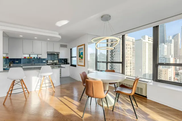 a kitchen with stainless steel appliances granite countertop a stove a refrigerator a dining table and chairs with wooden floor