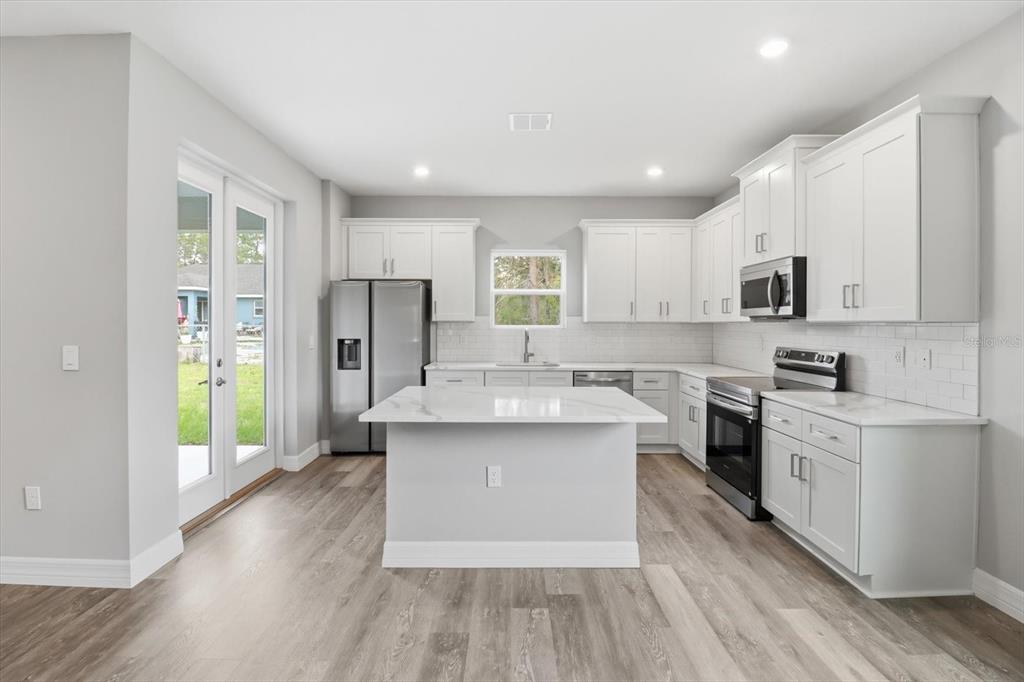 6349 Southwest 134th Loop Ocala, FL 34473 - Photo 12 of 45 a kitchen with stainless steel appliances a white stove top oven a sink dishwasher and a refrigerator with wooden floor