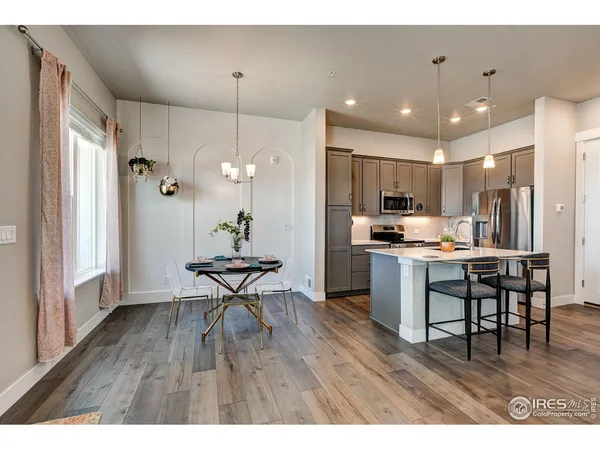 a kitchen with stainless steel appliances a dining table chairs refrigerator and microwave