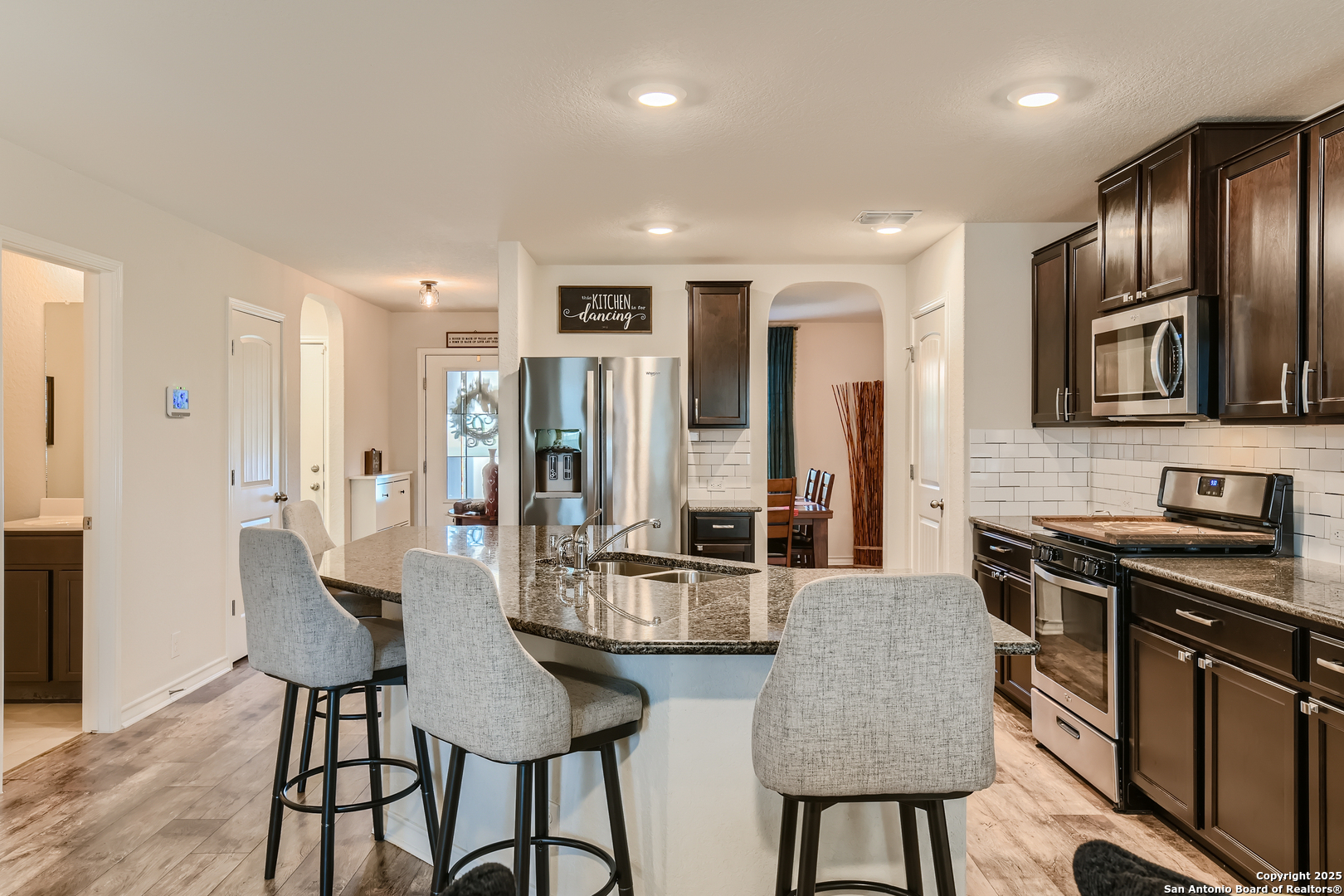 13322 Silky Rye San Antonio, TX 78254 - Photo 12 of 44 a kitchen with stainless steel appliances granite countertop a stove top oven a sink a refrigerator and chairs
