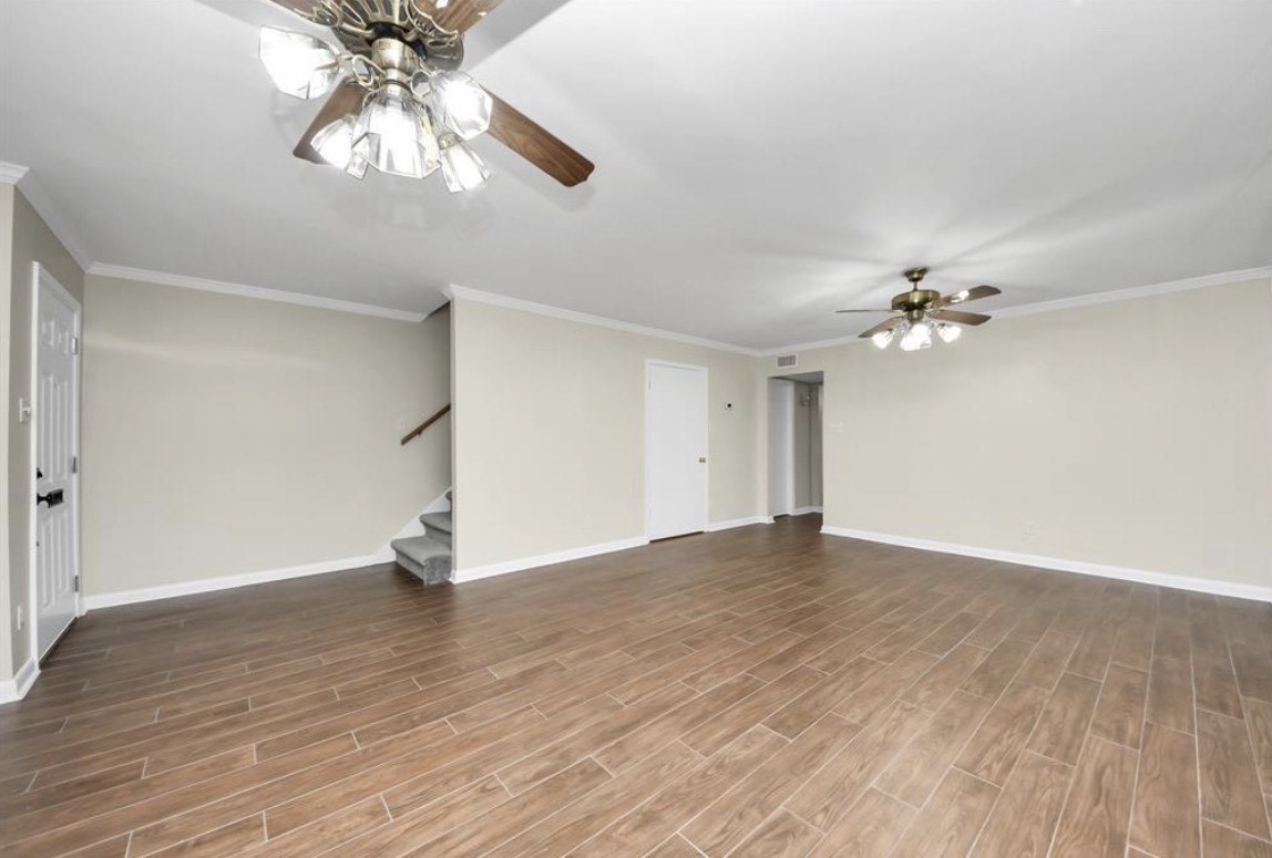 8234 Fondren Road, Unit 8234 Houston, TX 77074 - Photo 3 of 10 an empty room with wooden floor chandelier fan and view of a room