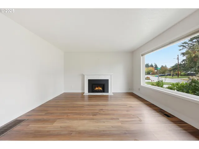 a view of an empty room with a window and fire place