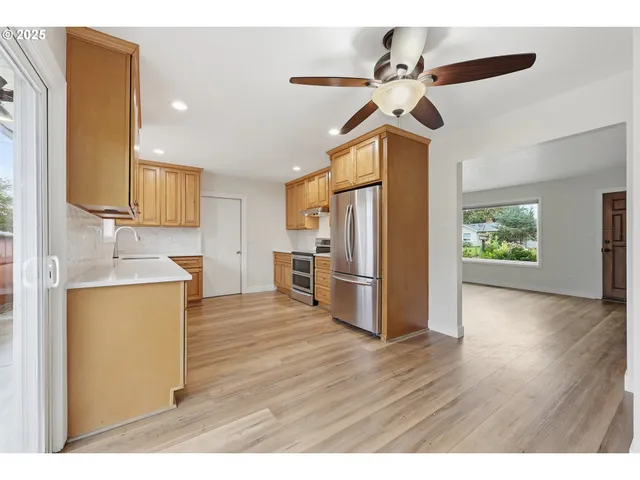 a kitchen with stainless steel appliances a refrigerator a sink dishwasher a oven with wooden floor and cabinets