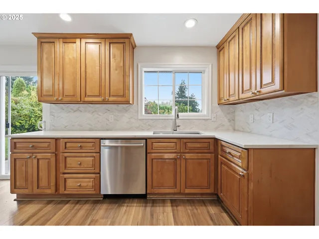 a kitchen with stainless steel appliances granite countertop a sink cabinets and a large window