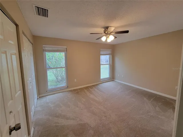 an empty room with windows and fan