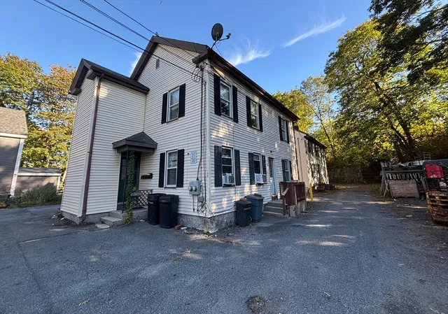 a view of a house with a barbeque and large trees