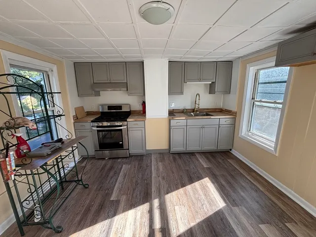 a kitchen with stainless steel appliances granite countertop a stove top oven a sink dishwasher and a refrigerator with wooden floor