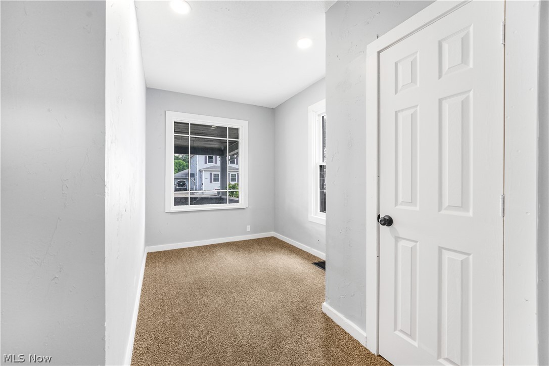885 Wales Road Northeast Massillon, OH 44646 - Photo 7 of 34 Carpeted interior space with a paneled door, recessed lighting, and white trim