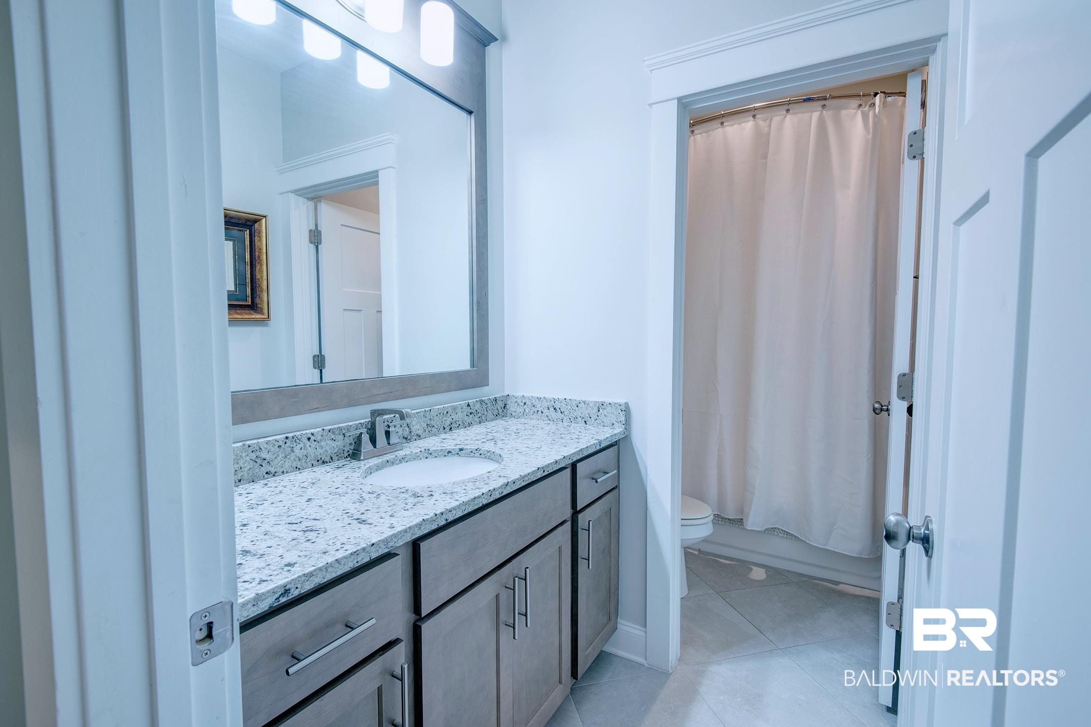 18754 Treasure Oaks Road Gulf Shores, AL 36542 - Photo 23 of 53 Bathroom vanity with a light-toned stone countertop and undermount sink