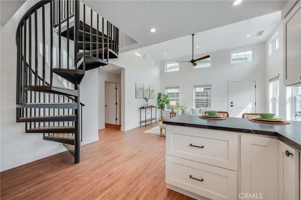 a kitchen with granite countertop a stove a sink and white cabinets with wooden floor
