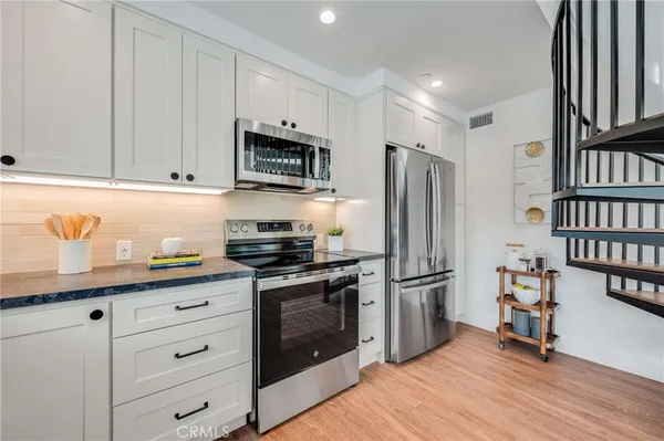 a kitchen with granite countertop a refrigerator stove and cabinets