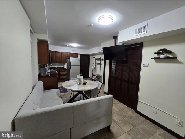 a living room with furniture and a refrigerator