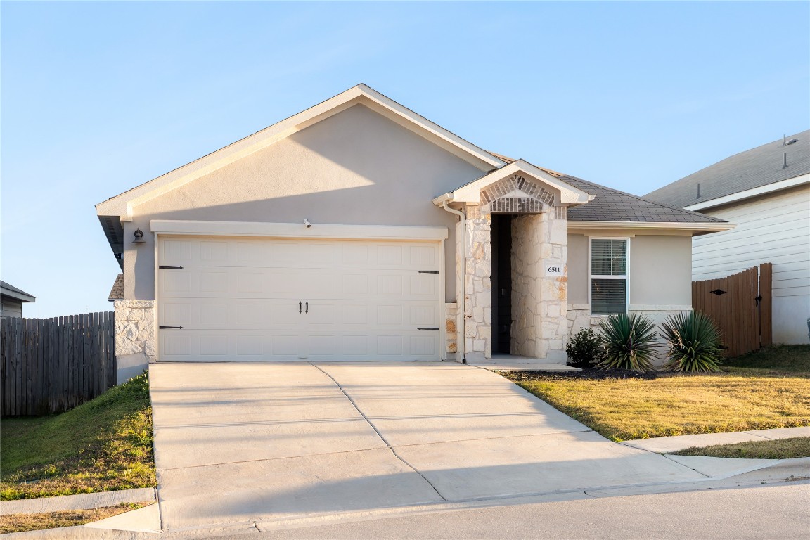6511 Rounded Pebble Lane Buda, TX 78610 - Photo 9 of 25 Ranch-style house featuring stone siding, stucco siding, concrete driveway, and an attached garage