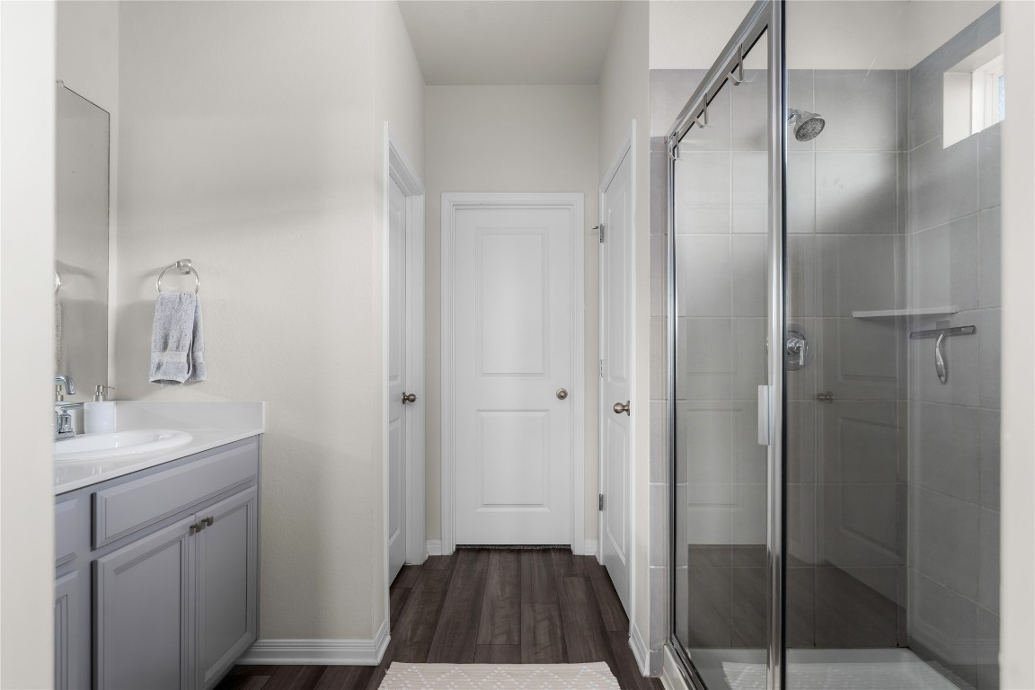6511 Rounded Pebble Lane Buda, TX 78610 - Photo 14 of 25 Full bathroom featuring a shower stall, vanity, and dark wood-style flooring