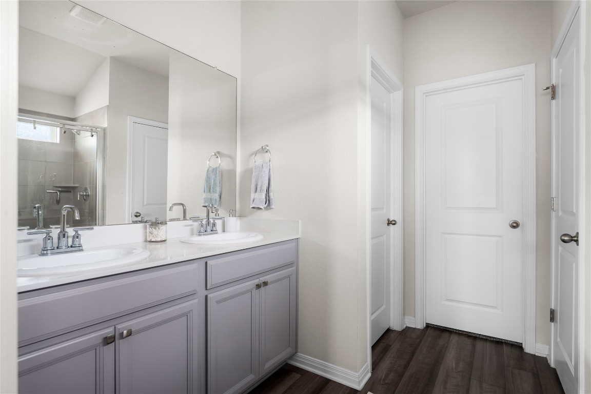 6511 Rounded Pebble Lane Buda, TX 78610 - Photo 15 of 25 Full bath featuring double vanity, a stall shower, and dark wood-style flooring