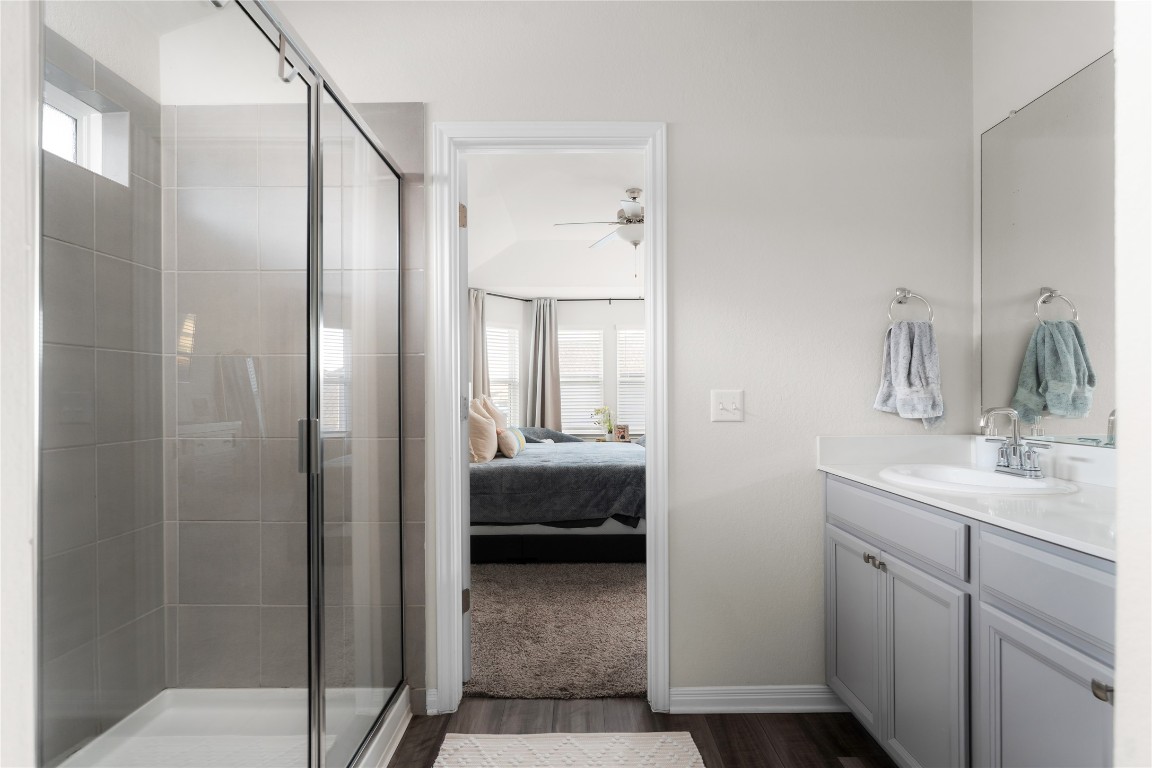 6511 Rounded Pebble Lane Buda, TX 78610 - Photo 16 of 25 Ensuite bathroom with a shower stall, healthy amount of natural light, vanity, and dark wood-style flooring