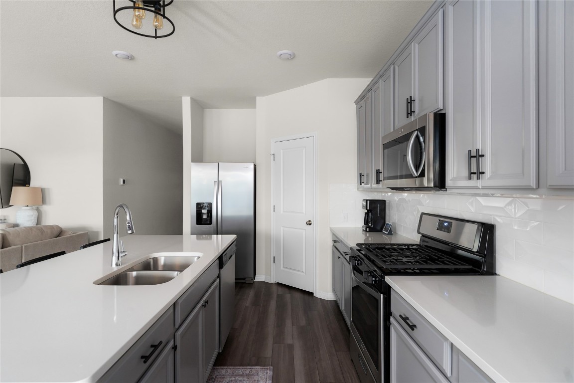 6511 Rounded Pebble Lane Buda, TX 78610 - Photo 24 of 25 Kitchen featuring stainless steel appliances, gray cabinetry, open floor plan, and dark wood-style flooring